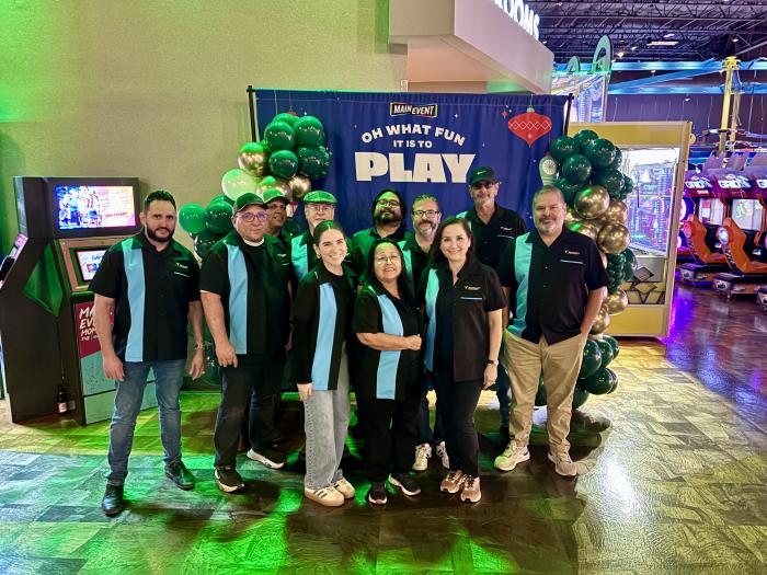 A group at a Main Event corporate party wearing custom black bowling shirts with a blue vertical stripe and company logo