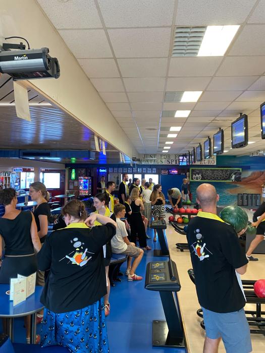 Bowlers at an alley showing off custom black and yellow shirts with a large screen printed bowling logo on the back