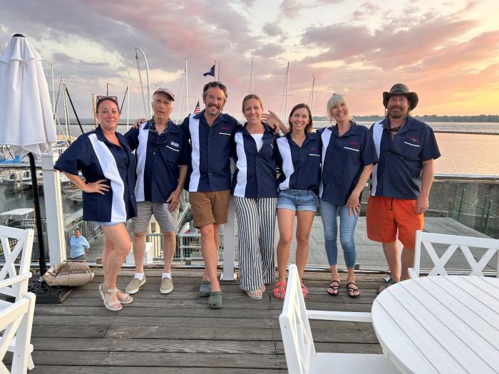 Group of men and women wearing custom bowling shirts at a marina during sunset
