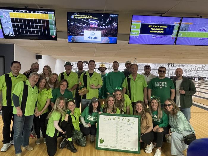 Large group posing in neon green and black custom bowling shirts for an annual corporate tournament celebration